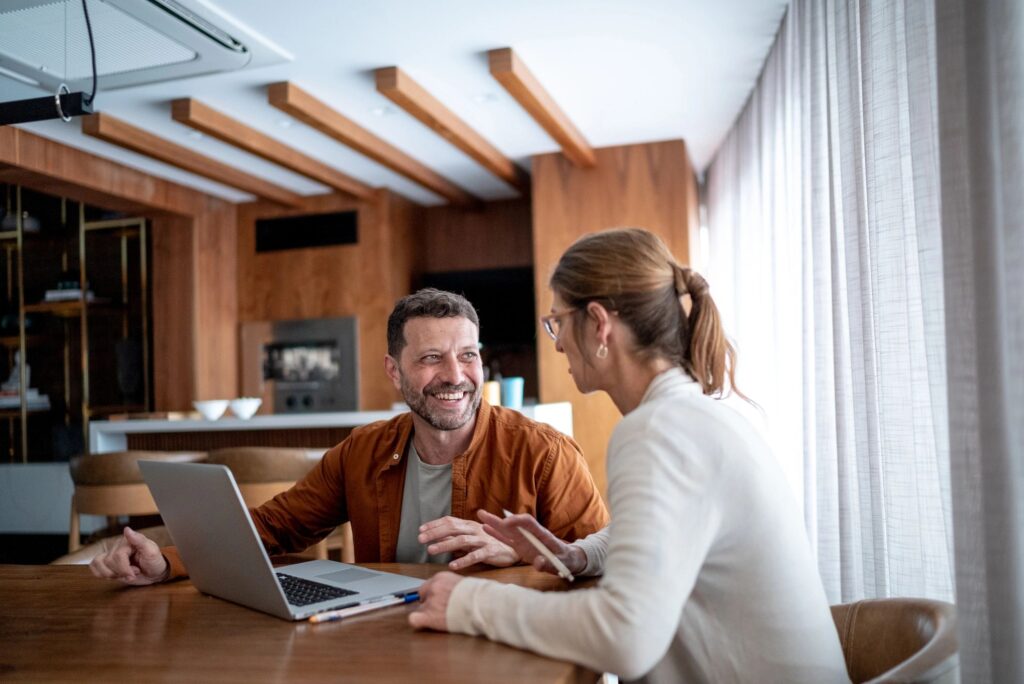 Mature couple talking and using the laptop at home